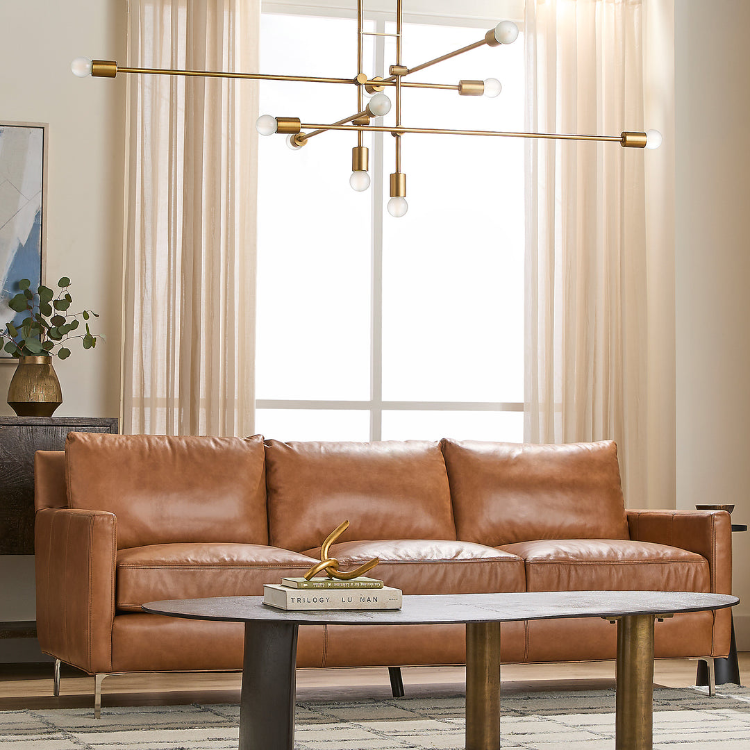 Brown leather sofa in a living room with a modern chandelier and decor.