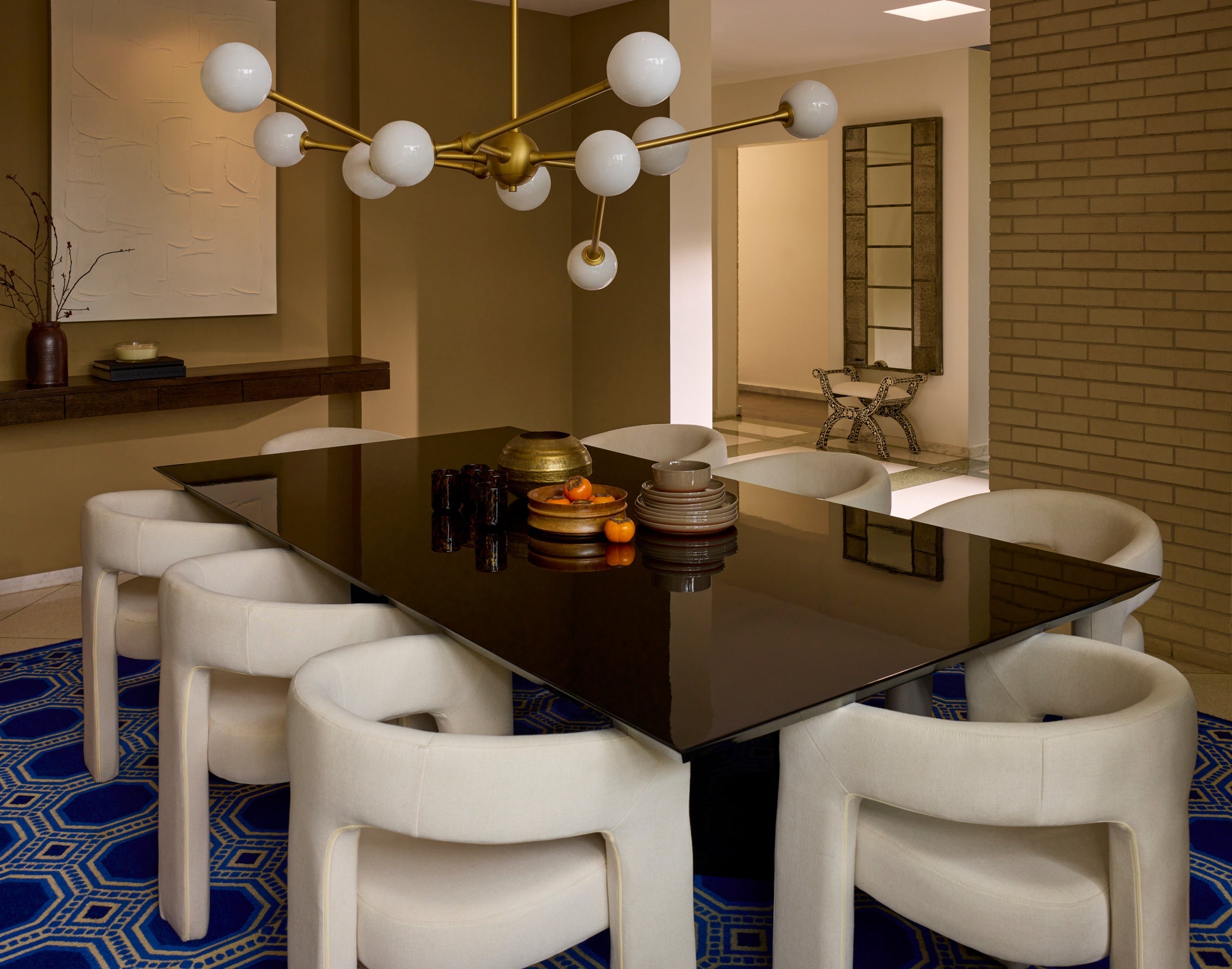 Modern dining room with a dark glass table and white chairs, featuring a stylish chandelier.